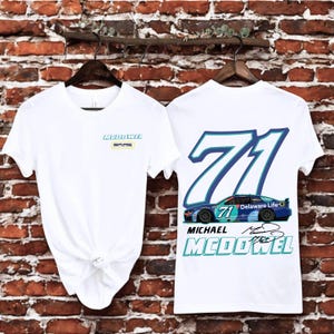 May include: White t-shirts with racing-themed graphics. One shirt features the text "McDowell SPME" on the front. The other shirt displays the number "71" with a race car graphic and the text "Delaware Life" and "Michael McDowell".