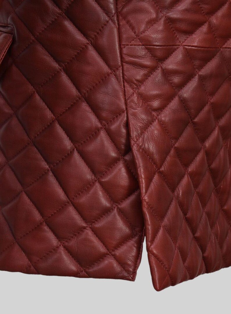 K&ouml;nnte beinhalten: Nahaufnahme einer burgunderfarbenen, gesteppten Lederjacke. Die Jacke hat ein Rautenmuster und einen Schlitz am unteren Saum. Das Leder hat einen leichten Glanz, und die N&auml;hte sind sichtbar.