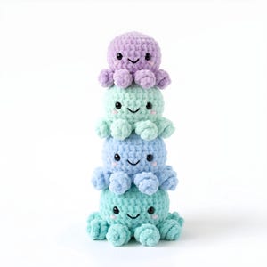 Pode incluir: Uma pilha de quatro brinquedos de polvo de croch&ecirc; em tons de roxo, verde menta, azul claro e azul-petr&oacute;leo. Cada polvo tem um rosto sorridente com olhos pretos e uma boca curvada. Os brinquedos s&atilde;o empilhados uns sobre os outros.
