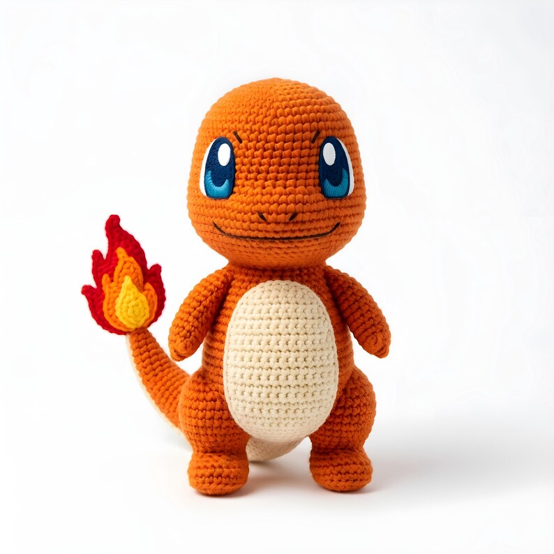 Pode incluir: Um brinquedo de pel&uacute;cia Charmander laranja feito &agrave; m&atilde;o com croch&ecirc;, com olhos azuis e uma cauda de chama. A pel&uacute;cia tem uma barriga creme e est&aacute; sobre um fundo branco. O brinquedo tem aproximadamente 20 cm de altura.