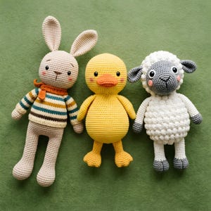 Pode incluir: Tr&ecirc;s animais de pel&uacute;cia de croch&ecirc; feitos &agrave; m&atilde;o: um coelho bege com um su&eacute;ter listrado e um cachecol laranja, um pato amarelo e uma ovelha branca com detalhes cinza. Os brinquedos est&atilde;o dispostos em uma superf&iacute;cie verde.