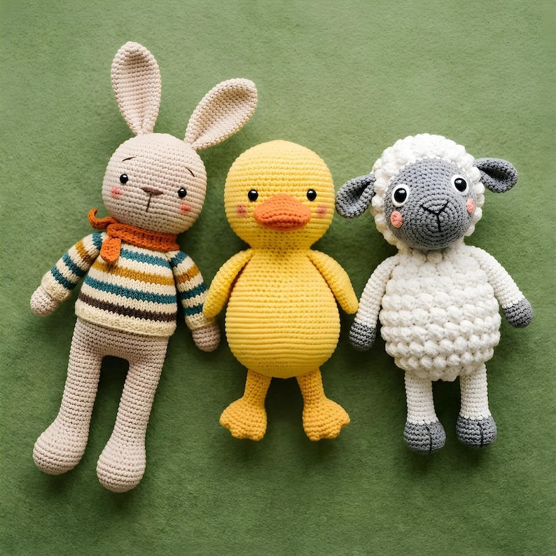 Pode incluir: Tr&ecirc;s animais de pel&uacute;cia de croch&ecirc; feitos &agrave; m&atilde;o: um coelho bege com um su&eacute;ter listrado e um cachecol laranja, um pato amarelo e uma ovelha branca com detalhes cinza. Os brinquedos est&atilde;o dispostos em uma superf&iacute;cie verde.