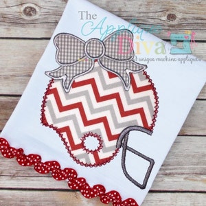 Könnte beinhalten: Ein weißer Stoff mit einem Applikations-Footballhelm in Chevron-Muster in Rot und Grau und einer Schleife aus grauem Gingham. Der Stoff hat einen roten und weißen gewellten Rand.