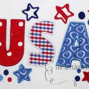 May include: Red, white and blue felt appliqué letters spelling "USA" with a gingham pattern on the "S" and a heart pattern on the "A".