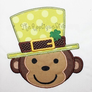 Può includere: Disegno ricamato di una scimmia che indossa un cappello verde e giallo a pois con una cintura marrone e un trifoglio verde.