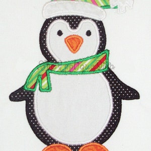 Puede incluir: Un pingüino blanco con lunares negros, que lleva una bufanda a rayas verdes y rojas y un gorro a rayas verdes, rojas y blancas con un pompón blanco.