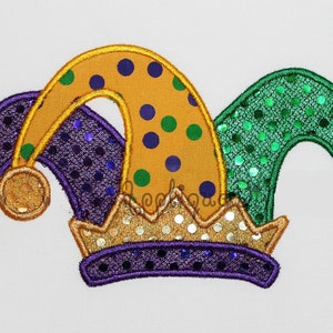 May include: A purple, green and gold jester hat with bells and sequins. The hat is a traditional Mardi Gras costume accessory.