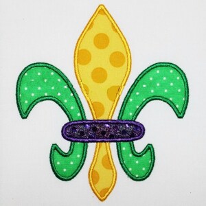 Peut inclure: Un lys vert et jaune avec des pois blancs. Le lys a une bande violette avec des paillettes autour du centre.