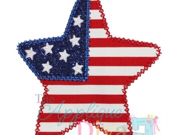 Pode incluir: Um remendo em forma de estrela vermelho, branco e azul com acabamento brilhante. A estrela é decorada com uma estrela azul menor com estrelas brancas dentro, que se assemelha à bandeira americana.