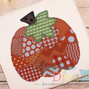 Könnte beinhalten: Eine Patchwork-Kürbis-Applikation mit braunem Stiel und grünen Blättern. Der Kürbis besteht aus verschiedenen Stoffresten in Orange, Rot, Weiß und Blau.