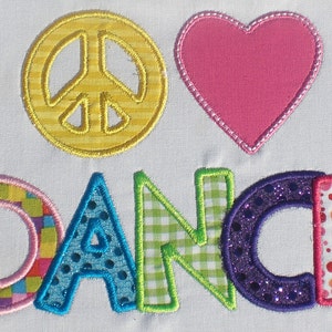 Può includere: Un design ricamato colorato con un segno di pace, un cuore e la parola "DANCE". Il segno di pace è giallo con un motivo a righe, il cuore è rosa e le lettere sono fatte di diversi tessuti a motivi.