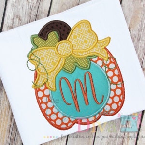 May include: An orange and white polka dot pumpkin with a yellow bow and green leaves. The pumpkin has a turquoise circle with the letter "M" in the center.