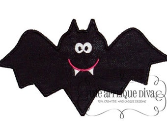 Puede incluir: Murciélago de fieltro negro con una cara sonriente y colmillos. El murciélago tiene ojos blancos y una boca rosa.