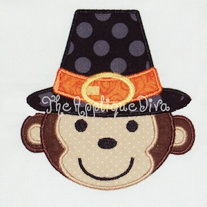 May include: Embroidered applique of a brown monkey wearing a black and white polka dot pilgrim hat with an orange and gold buckle. The monkey has a brown face with a white background and a stitched smile.