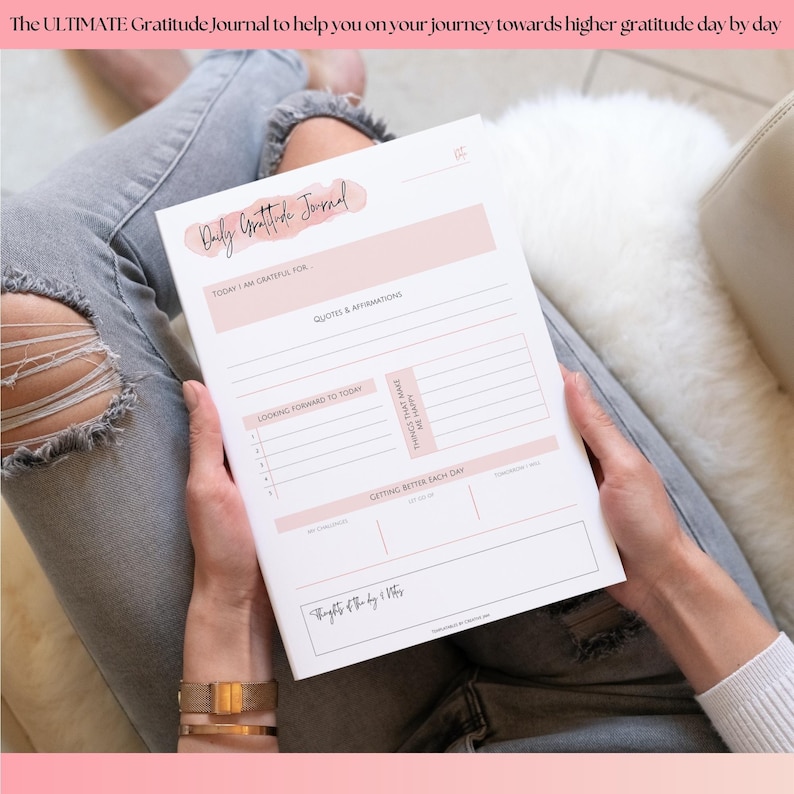 May include: A Daily Gratitude Journal with a pink and white design. The journal includes sections for gratitude, affirmations, and daily reflections. The text "The ULTIMATE Gratitude Journal" is at the top.