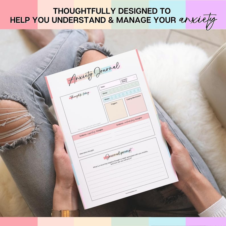 May include: A white Anxiety Journal with pink, blue, and yellow accents is held open. The journal includes prompts for tracking thoughts, feelings, and coping mechanisms. The text at the top reads, "THOUGHTFULLY DESIGNED TO HELP YOU UNDERSTAND & MANAGE YOUR anxiety."