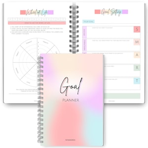 May include: A spiral-bound goal planner with a soft pastel gradient cover. The cover features the word "Goal" in elegant script above "Planner." The open planner reveals pages for goal setting and a "Wheel of Life" exercise.
