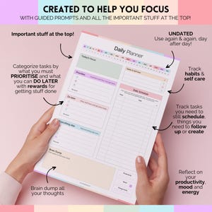 Puede incluir: Un planificador diario con una combinaci&oacute;n de colores pastel, sostenido por manos. El planificador incluye secciones para prioridades, horarios diarios y seguimiento de h&aacute;bitos. El texto en el planificador dice "Created to Help You Focus" y "Undated, Use again & again, day after day!"