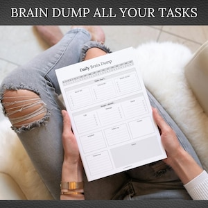May include: A Daily Brain Dump notepad with sections for tasks, calls, and notes. The notepad is held by a person wearing a gold watch and bracelets, with the text "BRAIN DUMP ALL YOUR TASKS" at the top.