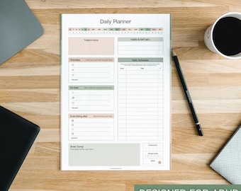 May include: A white daily planner with sections for focus, priorities, and a daily schedule. The planner has a green and beige color scheme, with the text "Daily Planner" at the top. The bottom right corner reads "DESIGNED FOR ADHD".