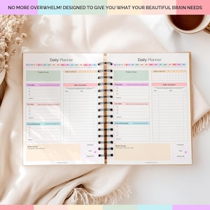 Puede incluir: Planificador diario abierto con encuadernaci&oacute;n en espiral. El planificador incluye secciones para horarios diarios, prioridades y un "brain dump". El texto "NO MORE OVERWHELM! DESIGNED TO GIVE YOU WHAT YOUR BEAUTIFUL BRAIN NEEDS" est&aacute; en la parte superior.