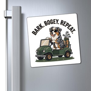 May include: A square magnet featuring a blue merle Australian Shepherd wearing black sunglasses, driving a green golf cart with a golf bag in the back. The text BARK. BOGEY. REPEAT. is printed in black capital letters above the dog.