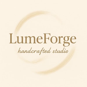 May include: A logo for LumeForge, a handcrafted studio, features a gold-colored font and a brushstroke circle on a cream background. The text includes the brand name and the tagline, creating a simple yet elegant design.