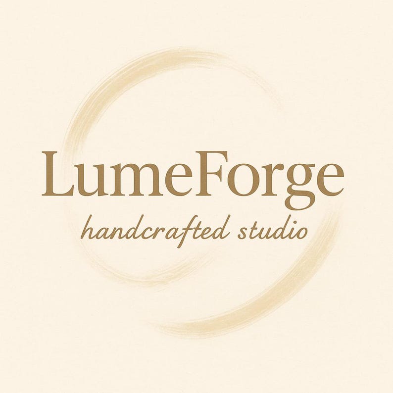 May include: A logo for LumeForge, a handcrafted studio, features a gold-colored font and a brushstroke circle on a cream background. The text includes the brand name and the tagline, creating a simple yet elegant design.