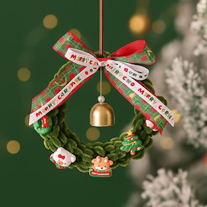 May include: A festive Christmas wreath with a green, plush base. It features a red and green plaid ribbon with "Merry Christmas" text, a gold bell, and small decorative ornaments. The wreath is designed for holiday decor.