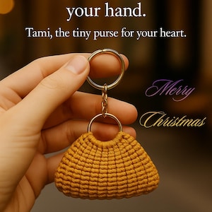 Puede incluir: Un pequeño llavero de bolso tejido en color mostaza con un anillo y cadena dorados. El texto dice "Tami, el pequeño bolso para tu corazón." y "Feliz Navidad."