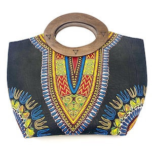 May include: A black tote bag with a colorful, patterned design and a wooden handle. The pattern features yellow, red, blue, and green geometric shapes. The handle is a large, round wooden ring.