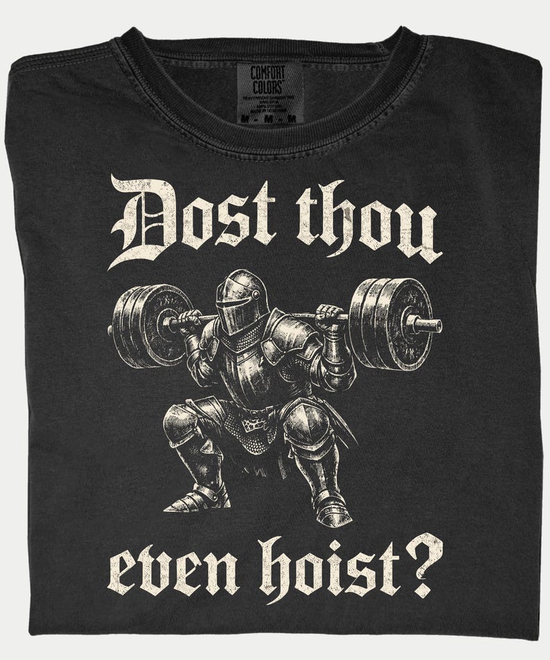 K&ouml;nnte beinhalten: Schwarzes T-Shirt mit einer Grafik eines Ritters in R&uuml;stung, der eine Langhantel hebt. Der Text "Dost thou even hoist?" ist oberhalb und unterhalb der Ritterillustration in gotischer Schrift gedruckt. Das T-Shirt hat ein Comfort Colors-Etikett.