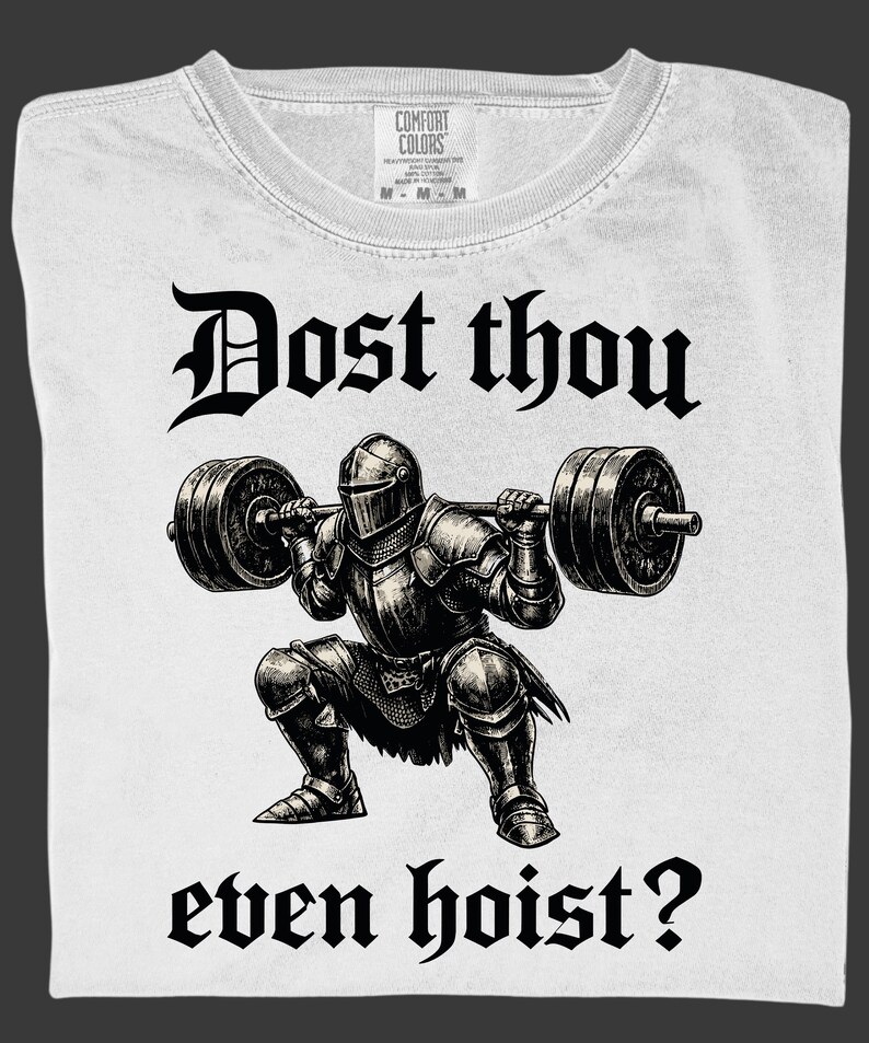 K&ouml;nnte beinhalten: Wei&szlig;es T-Shirt mit einem schwarzen Grafik eines Ritters, der Gewichte hebt, mit dem Text "Dost thou even hoist?" in gotischer Schrift. Das Shirt hat einen Rundhalsausschnitt und ein Etikett "Comfort Colors".