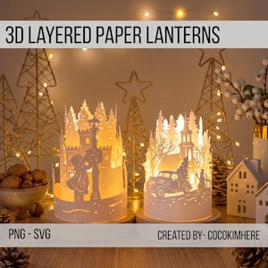 May include: Two cylindrical 3D layered paper lanterns featuring intricate white cut-out designs. One lantern depicts a person by a lamppost and castle, the other shows a vintage car with a tree and a church. Both are illuminated from within.