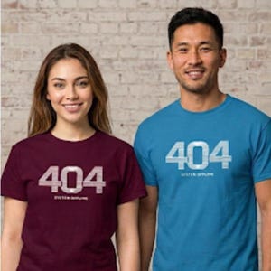 Può includere: Una t-shirt bordeaux e una t-shirt blu, entrambe con la scritta 404 SYSTEM-OFFLINE stampata in un carattere chiaro a righe orizzontali sul petto. Entrambi i capi hanno maniche corte e scollo rotondo, con disegni grafici identici.
