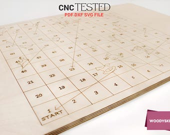 May include: A wooden board game with a grid of numbered squares and etched pathways. The board features the text "CNC TESTED PDF DXF SVG FILE" and "START". The game board is made of light-colored wood.