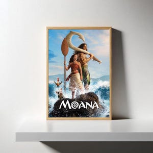 May include: Framed poster featuring characters from the animated film Moana. The artwork depicts two main characters standing on a rock in front of ocean waves. The title "Moana" is displayed in white text at the bottom.