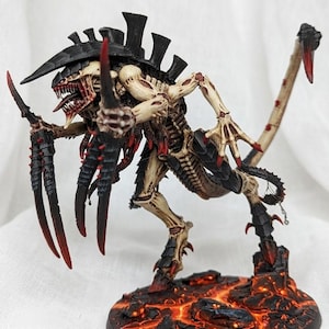 May include: A detailed miniature figure of a Tyranid creature, featuring a bone-colored body with black and red accents. The figure has sharp claws, a menacing head, and stands on a textured, lava-like base, showcasing intricate details.