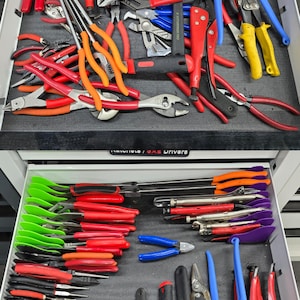 May include: Two stacked tool chest drawers containing a variety of hand tools. The top drawer holds assorted pliers and locking clamps with red, orange, and blue handles. The bottom drawer features organized pliers with green, red, and black handles.