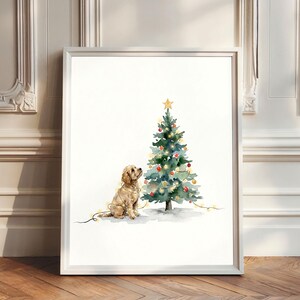 Pode incluir: Uma impressão em aguarela emoldurada com um cão de cor dourada sentado ao lado de uma árvore de Natal decorada. A árvore está adornada com enfeites vermelhos e dourados, luzes brilhantes e uma estrela amarela. O cão está enrolado em luzes.