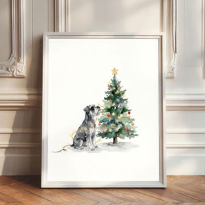 Pode incluir: Uma impressão em aguarela emoldurada apresentando um cão Schnauzer cinzento e preto sentado ao lado de uma árvore de Natal verde decorada com ornamentos vermelhos e dourados, luzes amarelas e uma estrela dourada, num fundo branco.