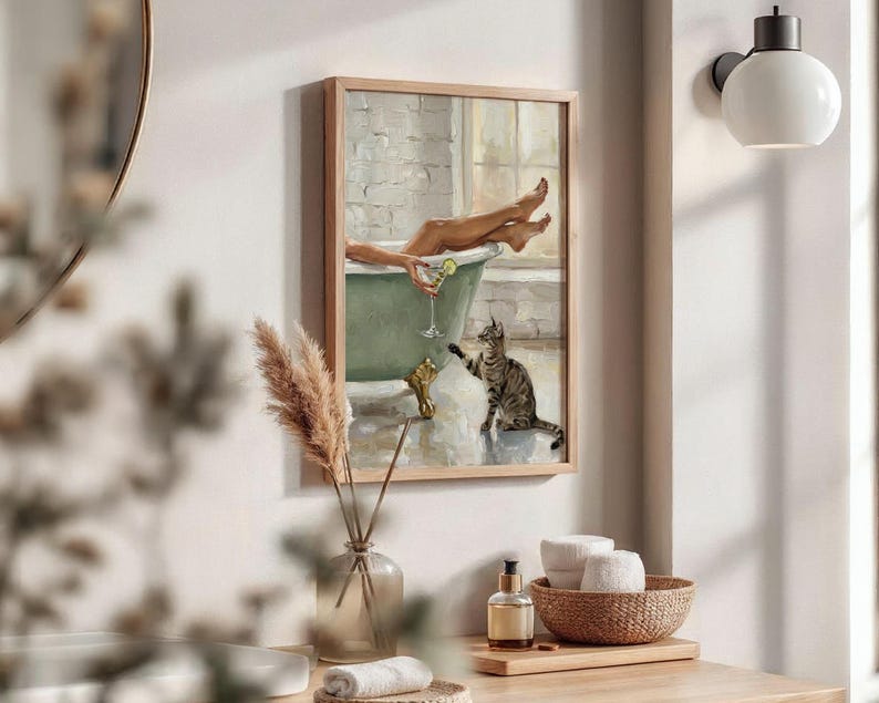 Op de afbeelding: Een ingelijst schilderij toont een persoon in een groene badkuip met een cocktail en een kat. Het kunstwerk heeft een lichte houten lijst en is aan een witte muur bevestigd. Het schilderij heeft een vintage, ontspannen thema.