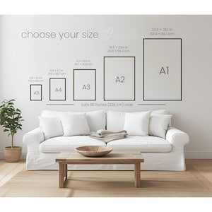Op de afbeelding: Afbeelding met ingelijste kunstafdrukformaten A1, A2, A3, A4 en A5, met afmetingen in inches en centimeters. De tekst "choose your size" staat boven de frames. Een witte bank en een houten salontafel staan op de voorgrond.