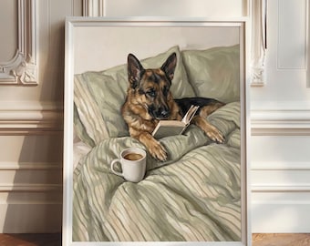 Puede incluir: Un cuadro enmarcado de un perro pastor alemán acostado en una cama con ropa de cama a rayas de color verde salvia. El perro apoya sus patas delanteras sobre un libro abierto mientras una taza de cerámica blanca con café descansa sobre el edredón.