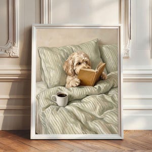 Può includere: Una stampa artistica da parete incorniciata che raffigura un cane dal pelo chiaro e riccio che riposa in un letto con biancheria a righe verde chiaro. Il cane tiene un libro aperto con le zampe e una tazza bianca di ceramica con caffè è sul letto.