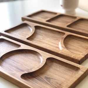 May include: Wooden serving platters with multiple compartments. The platters are crafted from light-coloured wood and feature rectangular, circular, and curved sections. Ideal for serving snacks or appetizers.
