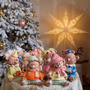 Könnte beinhalten: Eine Sammlung kleiner, texturierter Teddybär-Figuren, die bunte Schlafanzüge, Mützen und Schals tragen. Jeder Bär hat ein einzigartiges Outfit in Gelb-, Orange-, Blau- und Rosatönen, wobei einige kleine Geschenke oder Zuckerstangen in den Händen halten.