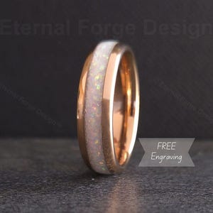 May include: A rose gold ring with a white opal inlay. The ring has a polished finish and features the text "FREE Engraving". The ring is a piece of jewelry.