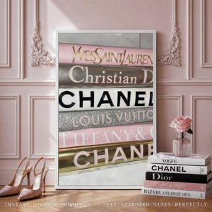 May include: A framed vertical wall art print featuring a stack of books with luxury brand names including Yves Saint Laurent, Christian Dior, Chanel, Louis Vuitton, and Tiffany & Co. The print is displayed next to a stack of real books and heels.