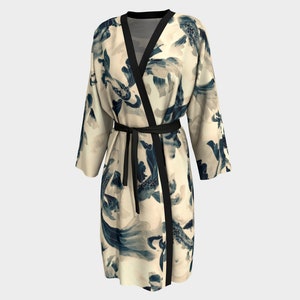 May include: A cream-colored robe with a black sash and a blue and white floral print. The robe has long sleeves and a wrap-around style.